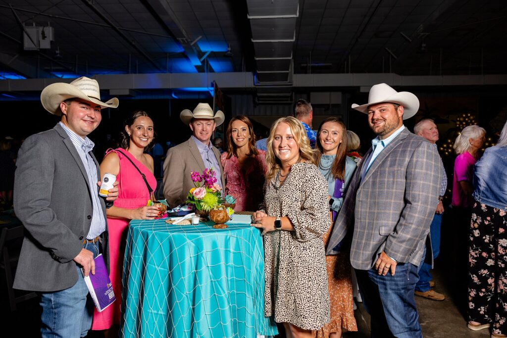 Friends gathered around the silent auction tables at Boots and Bling, discussing and placing bids on various items."